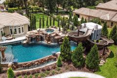 Panoramic shot of an elaborate waterslide installation with poolside greenery.