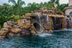 Close-up of a backyard waterslide with  natural stone and lush greenery .