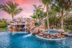 Wide-angle shot of a resort-inspired waterslide winding through custom pool landscaping.