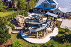 High vantage view of a custom waterslide spiraling into a lagoon-style pool design.