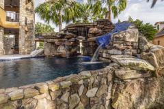Sunlit luxury waterslide and pool area with seamless integration into backyard hardscape.
