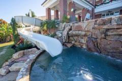 Poolside view of a slide exit area with natural rock infinity edge