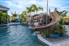 Close-up of a backyard waterslide with  natural stone and lush greenery .