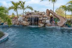 Waterslide beside a cascading waterfall feature over rugged stone accents.