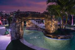 Signature Series Insane Pool with natural rock rain curtain at night