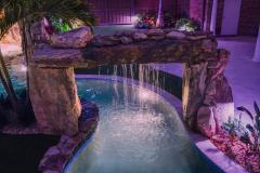 Signature Series Insane Pool with natural rock rain curtain at night